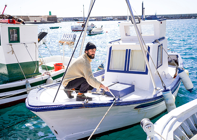 The sailor boards the fishing boat, tying down the ropes in the harbor.